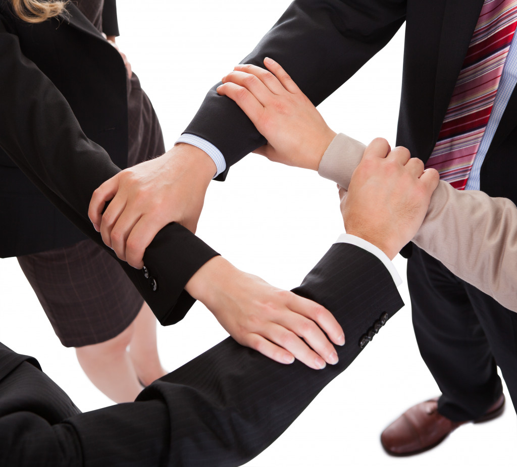 Four business professionals linking hands for collaboration