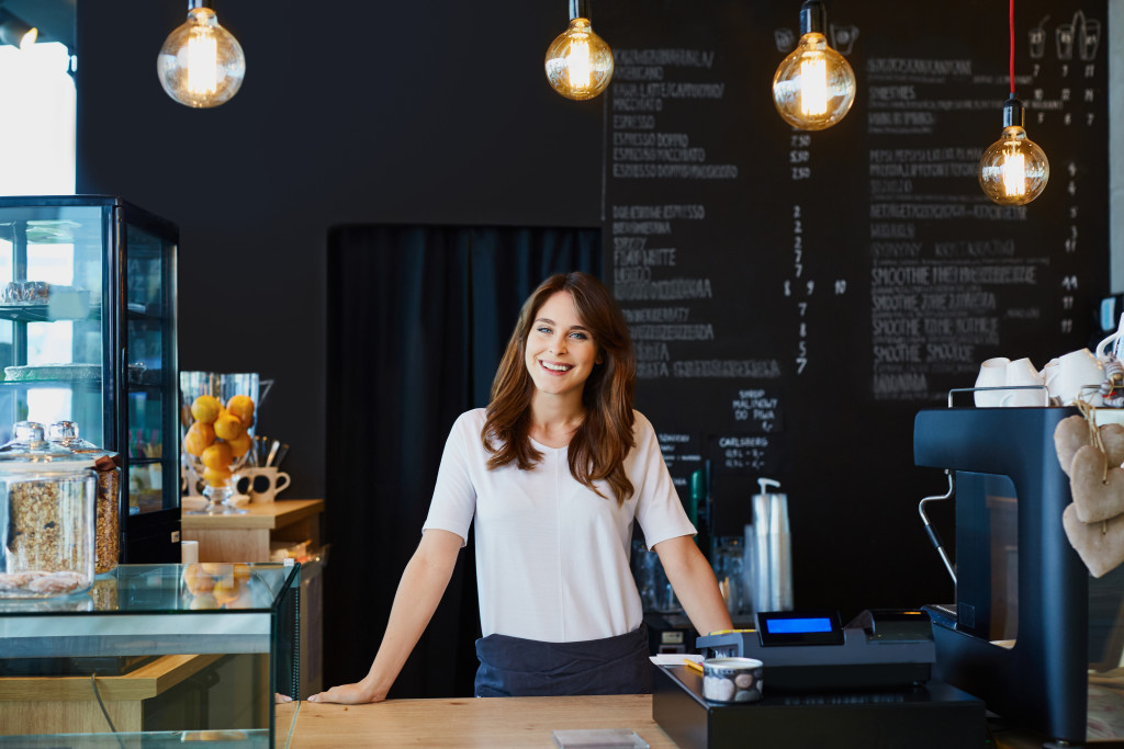 Female business owner standing behind the counter of a coffee shop.